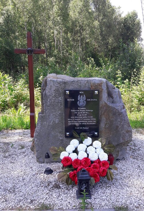 Pomnik w formie głazu, przy którym stoi, przewyższający go, drewniany krzyż z podobizną Chrystusa; na pomniku czarna tablica inskrypcyjna ku czci żołnierzy Wojska Polskiego, przed nim - bukiet biało-czerwonych kwiatów; w tle las