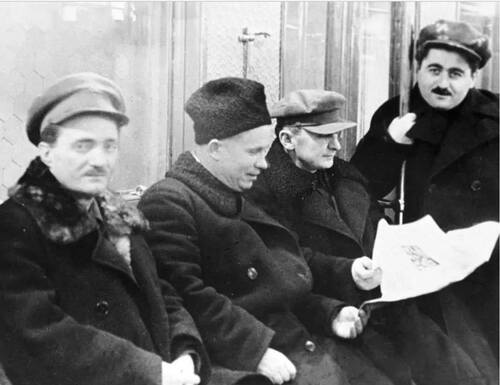 Nikita Chruszczow i Ławrientij Beria na zdjęciu, na którym jest jeszcze dwóch innych mężczyzn. Wszyscy ubrani są w zimowe płaszcze, trzech ma na głowach kaszkiety, Chruszczow - zimową czapę. Beria i Chruszczow przeglądają gazetę. Moskwa, 1935 rok.