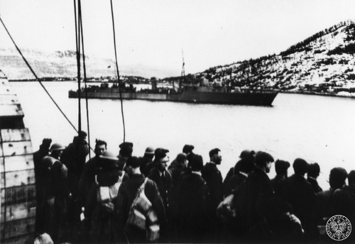 Brytyjscy żołnerze z jednostek lądowych na pokładzie transportowca po przybyciu do Norwegii (prawdopodobnie w rejonie Narwiku). W głębi fragment fiordu i stojący brytyjski duży niszczyciel typu "Tribal" - kwiecień 1940 r. Fot. AIPN