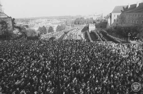 Ludzie zebrani na placu Zamkowym w Warszawie po zamachu na papieża Jana Pawła II, maj 1981. Widok w kierunku Wisły i Trasy W-Z. Fot. z zasobu IPN (z kolekcji fotografii Jana Hausbrandta)