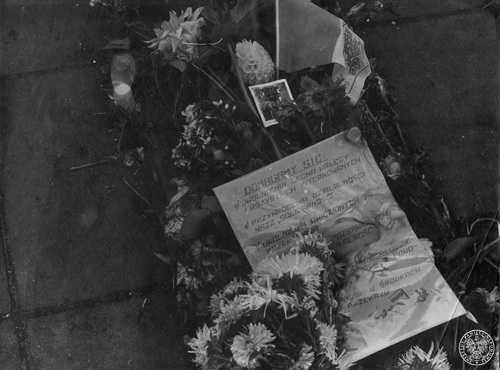 Kwiaty, obrazek z postacią Matki Bożej i ulotka sygnowana przez Solidarność, pod Bazyliką katedralną w Kielcach, wrzesień 1982 r. Fot. z zasobu AIPN