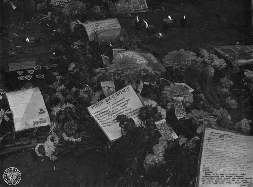Kwiaty, znicze, obrazki z postaciami świętych, tarcze szkolne, ulotki sygnowane przez "Solidarność", pod Bazyliką katedralną w Kielcach. Kartka z modlitwą w intencji internowanych, uwięzionych, prześladowanych, pozbawionych pracy, nauki, wygnanych z ojczystego kraju, wrzesień 1982 r. Fot. z zasobu AIPN