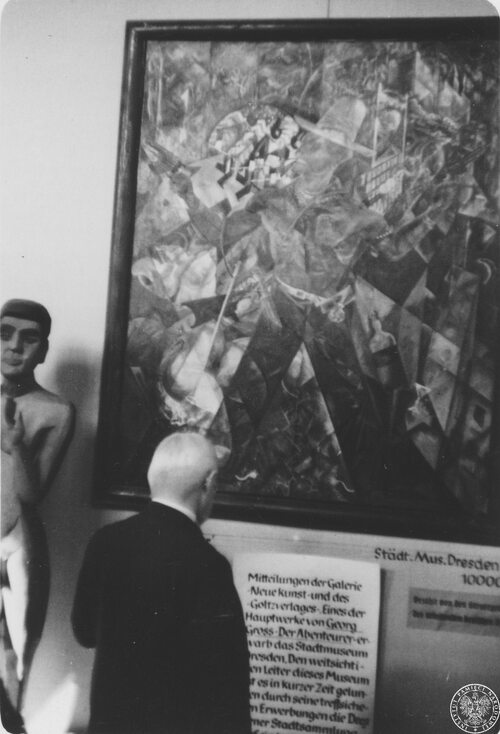 Mężczyzna ogląda obraz George’a Grosza „Der Abenteurer” (Poszukiwacz przygód) na wystawie „sztuki zdegenerowanej” w Monachium. Po lewej widoczny fragment rzeźby Ernsta Ludwiga Kirchnera „Das Paar“ (Para). Obecne miejsce przechowywania obu dzieł nieznane. Fot. Julien Bryan, AIPN/USHMM