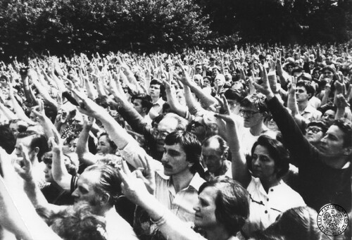 Tłumy z uniesionymi w geście zwycięstwa rękami.