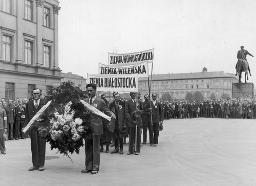 Uczestnicy wycieczki z ziem północno-wschodnich II RP z wieńcem na placu Marszałka Józefa Piłsudskiego w drodze do Grobu Nieznanego Żołnierza. W głębi widoczny pomnik księcia Józefa Poniatowskiego, październik 1934 r