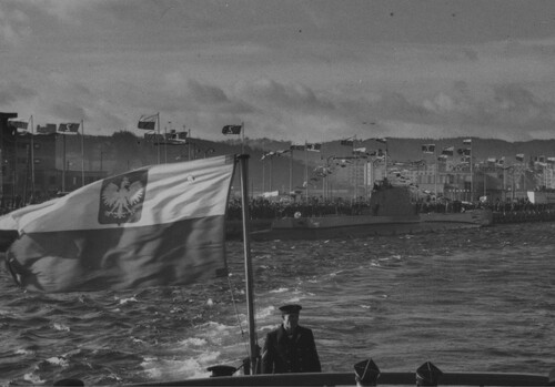 Powitanie okrętu podwodnego ORP „Orzeł” w porcie w Gdyni, 10 lutego 1939. ORP „Orzeł” przepływa obok nadbrzeża, przy którym witają go wiwatujące tłumy. Ze zbiorów NAC (autor:  Witold Pikiel)