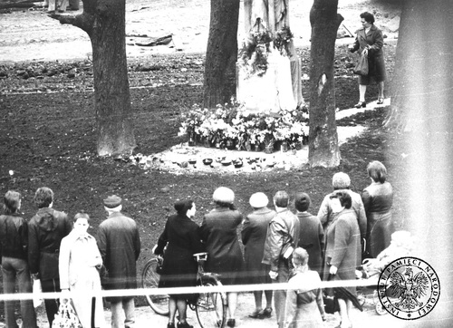Fotografia wykonana w trakcie obserwacji ludności gromadzącej się pod figurą kamiennego krzyża (widoczna cześć cokołu) w Tychach, 1979 r. Fot. z zasobu AIPN