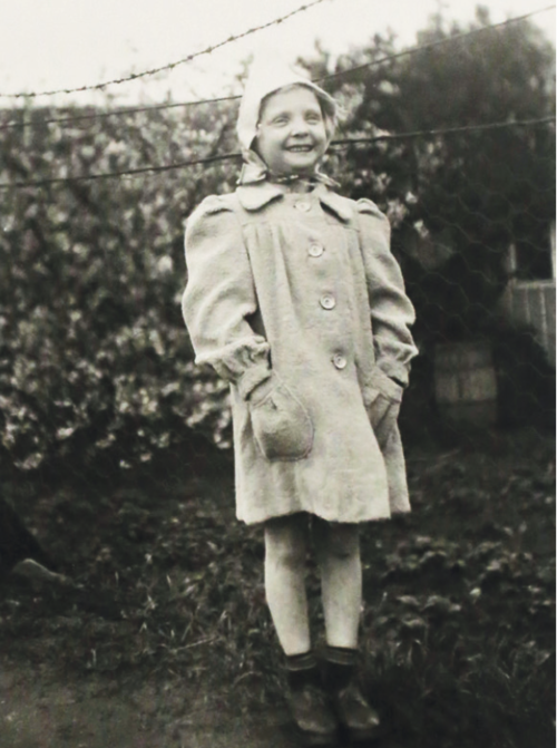 Zdjęcie małej dziewczynki w czapce na tle ogrodzenia