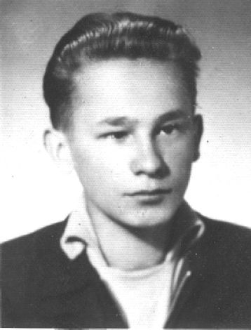 Fotografia portretowa młodego mężczyzny: włosy zaczesane do tyłu, kurtka, sweter, biała koszula z wywiniętymi kołnierzykami.
