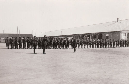 Żołnierze ustawieni w szeregu podczas apelu, na pierwszym planie dwóch żołnierzy składa meldunek, jeden z nich salutuje