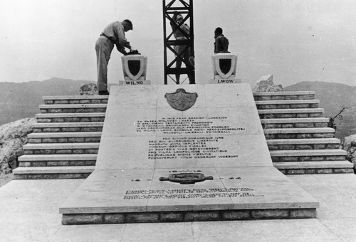 Pomnik 5. Kresowej Dywizji Piechoty na wzgórzu 575. Trójka żołnierzy obok dolnej cześci krzyża ustawionego na kamiennej podstawie postumentu. Krzyż wykonany ze stalowych kratownic. Obok krzyża umieszczono urny z tarczami herbowymi z podpisami Wilno i Lwów. Po obu stronach podstawy biegną schody. Na środku, inskrypcja przedzielona herbami: herb "Rzeczpospolitej Trojga Narodów" oraz tarcza z wizerunkiem żubra - symbolu dywizji.