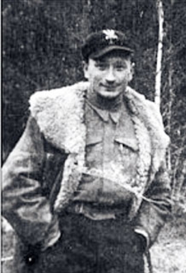Zdjęcie mężczyzny w lesie. Postać ubrana w kożuch i czapkę z przypiętym orzełkiem