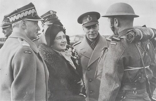 Na pierwszym planie uśmiechająca się kobieta w eleganckim ubraniu zimowym, w kapelusiku damskim i płaszczu z szerokim kołnierzem z futra, stoi pośrodku dwóch mężczyzn w zimowych (grube płaszcze) mundurach oficerskich. Przed nimi, tyłem, stoi i melduje coś żołnierz w hełmie. Widoczne naszywki ze słowem: „POLAND” na rękawach tego żołnierza oraz generała stojącego po prawej stronie kobiety. Z tyłu stoi jeszcze dwóch mężczyzn w polskich mundurach oficerskich.