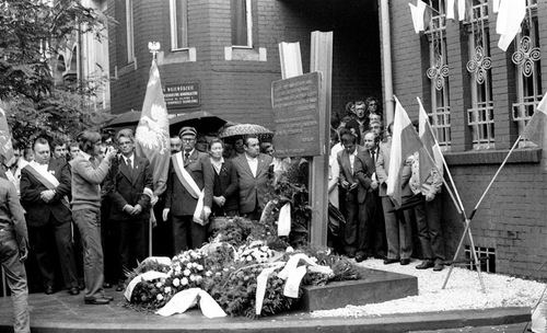 Uroczystość odsłonięcia tablicy pamiątkowej przy ul. Gajowej, w czasie obchodów 25. rocznicy Poznańskiego Czerwca 1956, 27 czerwca 1981 r. Grupa osób zgromadzona przy pomniku przed wejściem do ceglanego budynku. Wśród uczestników poczet sztandarowy. Pod pomnikiem złożone wieńce.