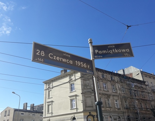 Skrzyżowanie ulic 28 czerwca 1956 r. i Pamiątkowej w Poznaniu. Drogowskaz z nazwami ulic na tle miejscowej zabudowy.