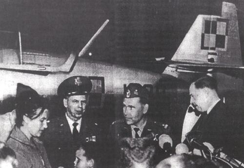Grupa mężczyzn stojących na tle samolotu (dwóch z nich w mundurach)
