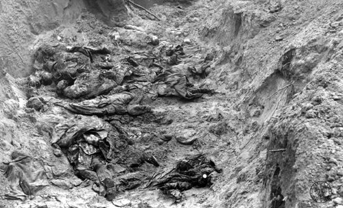 Las Katyński. Rozkopana w czasie ekshumacji mogiła zbiorowa ofiar ludobójstwa sowieckiego, w której znajdują się ludzkie szczątki w płaszczach i mundurach wojskowych.