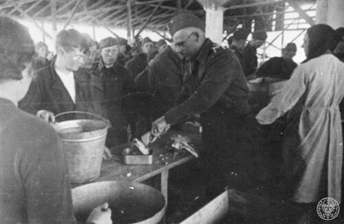Jeden z polskich obozów wojskowych Armii Polskiej w Związku Sowieckim, 1942 rok. Barak. Podoficer wydaje posiłki młodocianym żołnierzom - widok zza stołu. Za podoficerem ubrana w biały fartuch kobieta. Na stole stoi metalowe wiadro, obok drugie.