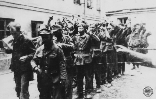 Grupa jeńców niemieckich wziętych do niewoli powstańczej po zdobyciu budynku PAST-y (ulica Zielna 39) na podwórzu kamienicy przy ulicy Zielnej 34 przed odprowadzeniem - zbliżenie od przodu; 20 sierpnia 1944 roku.