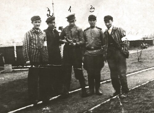 Ochotnicy Polskiego Czerwonego Krzyża z Brzeszcz: Zdzisław Bosek, Adam Kolanko, żołnierz szpitala sowieckiego, 1945 rok. Na zdjęciu widać w sumie pięciu mężczyzn. Dwóch z nich ma na sobie bluzy obozowe - pasiaki.