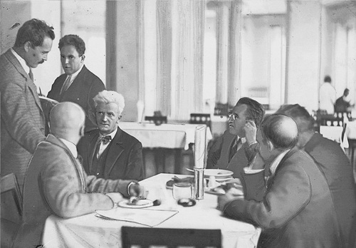 Dyskusja parlamentarzystów PPS w bufecie sejmowym. Widoczny poseł Zygmunt Zaremba (pierwszy z lewej), senator Andrzej Strug (siedzi drugi z lewej) oraz Adam Próchnik (stoi między Zarembą a Strugiem), 1929 r. Fot. z zasobu NAC