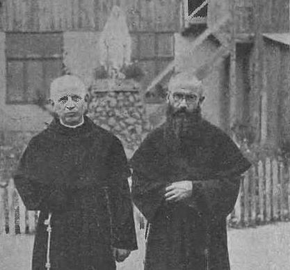 Ojciec Kornel Czupryk i o. Maksymilian Kolbe pozują do zdjęcia, w tle widoczna figura Matki Boskiej