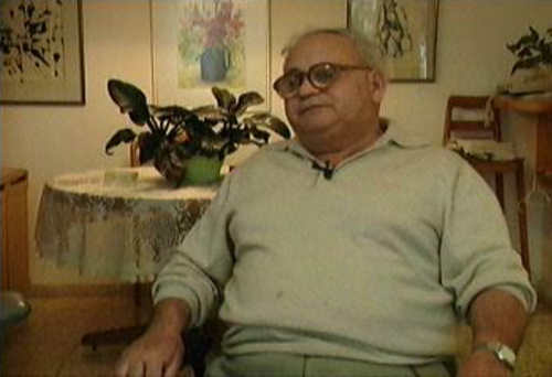 Zalman Kłodawski, starszy mężczyzna w dużych okularach, w pokoju, w trakcie nagrywania video-relacji, 7 maja 1996 roku.