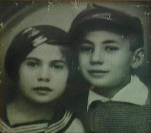 Zalman Kłodawski wraz z jedną z sióstr, w wieku dziecięcym, ubrani w stroje szkolne (chłopiec ma czapkę szkolną na głowie, dziewczynka ubrana jest w bluzkę z marynarskim kołnierzykiem). Zdjęcie przedwojenne.