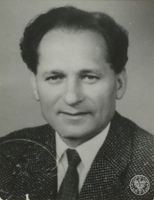 Mieczysław Moczar, szef Wojewódzkiego Urzędu Bezpieczeństwa Publicznego w Łodzi w latach 1945-1948. Na zdjęciu jest mężczyzna w średnim wieku, o głęboko osadzonych oczach, nieco rozwichrzonych, ciemnych włosach, wysokim czole, gładko ogolony, ubrany w białą koszulę, krawat i wełnianą marynarkę.