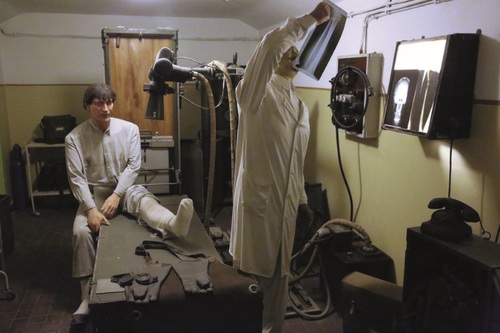 Rekonstrukcja gabinetu lekarskiego w Muzeum Szpitala w Skale. Manekiny lekarza i pacjenta w zaaranżowanym pomieszczeniu medycznym.