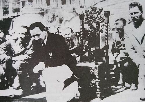 Bolesław Bierut klęczy podczas na mszy, w tle zdobiony reprezentacyjny fotel