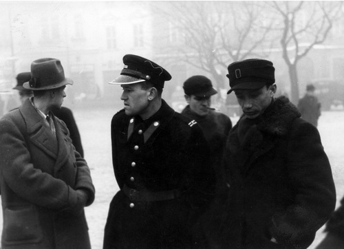 Policjant (granatowy) podczas rozmowy z mężczyznami na Rynku Głównym w Krakowie, 1940 r. Fot. ze zbiorów NAC