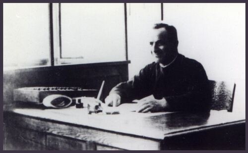 Zdjęcie ks. Kazimierza Kucharskiego pracującego przy biurku