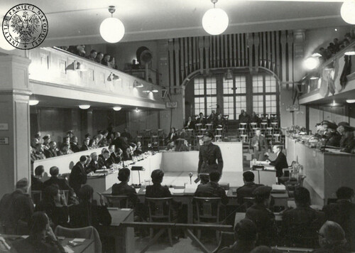 Sala sądowa procesu załogi KL Ravensbrück. Na zdjęciu widać dużą, oszkloną salę z galeriami. W sali są strefy dla: sędziów (siedzących za stołem), oskarżonych (siedzących na ławach), przed którymi siedzą ich obrońcy, protokolantów, korespondentów i widowni (która zasiada także na galeriach).