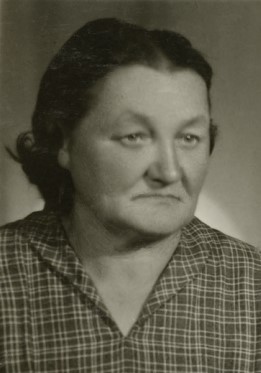 Maria Czerwień. Na zdjęciu jest starsza kobieta o nieco wydatniejszych policzkach, głębiej osadzonych oczach, z ciemnymi, zaczesanymi z przedziałkiem na środku głowy włosami, ubrana w kraciastą bluzkę.