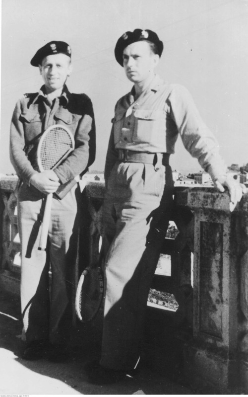 Dwóch żołnierzy (w mundurach) pozuje do zdjęcia, jeden z nich (po lewej) trzyma w ręku rakietę tenisową