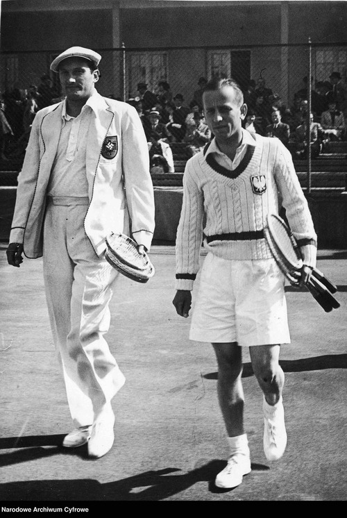 Dwóch mężczyzn, Ignacy Tłoczyński i  Roderich Menzl, w strojach tenisowych na korcie. Obaj trzymają w rękach tenisowe rakiety.