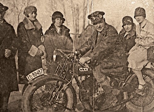 Ojciec Henryka Atemborskiego, ubrany w motocyklowy strój z epoki dwudziestolecia międzywojennego (skórzana kurtka, duży skórzany kaszkiet z nałożonymi nań goglami), na motocyklu BSA. Na zdjęciu widoczne także inne osoby: cztery kobiety, w tym jedna siedząca na motocyklu, oraz jeden mężczyzna. Wszystkie te osoby są ubrane bardzo elegancko. Fotografia ze zbiorów Autora.