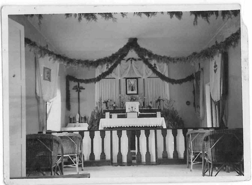 Wnętrze kaplicy, nad stołem ołtarzowym obraz zawieszony na ścianie wyścielonej białą tkaniną. Pod sufitem girlandy. Chorągwie oparte o ścianę, balaski, wiklinowe fotele. Digglefold (Płd. Rodezja) z lat 1944-1948, ze zbiorów AIPN