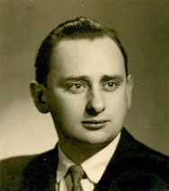 Bronisław Kazimierz Dyba w wieku 25 lat. Na zdjęciu jest młody, gładko ogolony mężczyzna o wysokim czole i ciemnych, zaczesanych do tyłu włosach; ubrany w ciemną marynarkę i białą koszulę oraz mający pod szyją krawat.