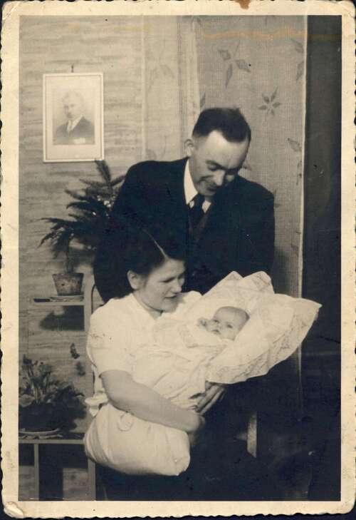 Kobieta i mężczyzna patrzą na niemowlę trzymane przez kobietę na rękach