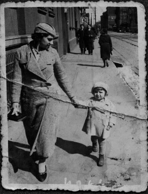 Zdjęcie kobiety idącej ulicą i prowadzącej dziecko za rękę