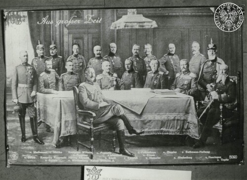Grupa mężczyzn w pruskich mundurach stojąca i siedząca wokół stołu