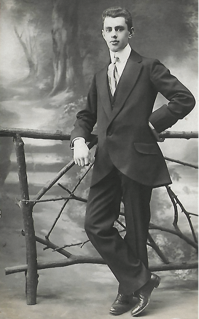 Młody Stefan Szletyński w garniturze pozuje do zdjęcia w studio fotograficznym