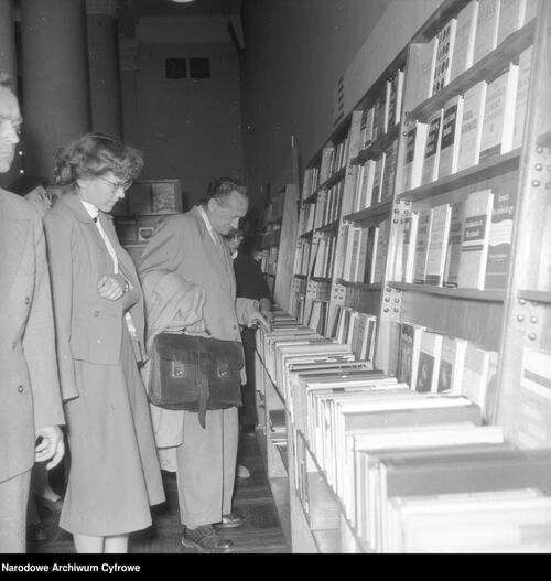 Kilka osób stojących przy półce z książkami i oglądających ofertę