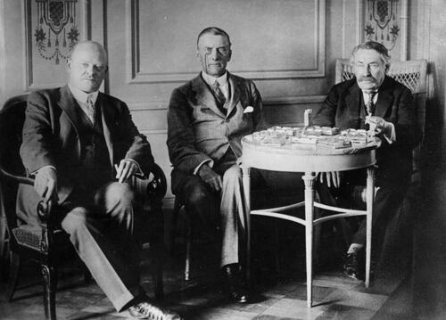 Trzech dyplomatów siedzących w fotelach pozuje do zdjęcia