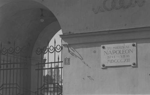 Tablica pamiątkowa ku czci Napoleona umieszczona na ścianie pałacu reprezentacyjnego w Wilnie (dawniej Biskupi) przy placu Napoleona 8 w Wilnie. W prześwicie bramy widoczne wieże kościoła św. Katarzyny na ulicy Wileńskiej, lata 30. XX w. Fot. z zasobu NAC