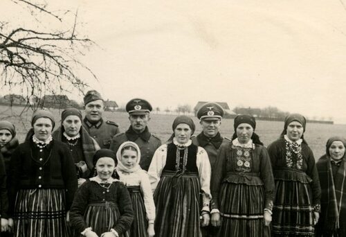 August Gauer (4 od prawej) i jego podwładni z Wehrmachtu pozują z grupą spotkanych polskich kobiet i dziewczynek ubranych w tradycyjne opaczyńskie stroje ludowe, prawdopodobnie okolice Spały, wiosna 1940 r. Z zasobu Archiwum IPN