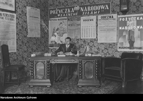 Stefan Starzyński jako generalny komisarz Pożyczki Narodowej. Nad nim, na tablicy, oraz na jednym z plakatów obok – hasło promujące akcję: Własnemi siłami