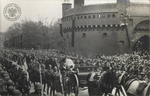 Kondukt pogrzebowy Józefa Piłsudskiego mijający krakowski Barbakan. Bezpośrednio za trumną widoczne żona i córki zmarłego, w żałobnych welonach. 18 maja 1935 r. Fot. z zasobu IPN